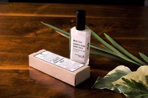 Bottle of beard growth mask filled with white liquid standing on a wooden surface alongside leaves