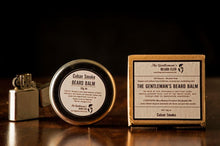 Round silver beard balm tin with old fashioned lighter and box standing upright next to each other