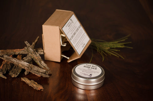 Beard balm tin laying flat on surface with square brown box in the background
