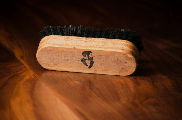 Wooden beard brush with logo on wooden surface