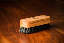 Beard brush with a wooden handle and black synthetic bristles