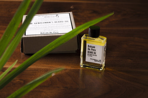Clear glass bottle filled with yellow beard oil with brown box in background