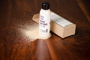 Bottle filled with white beard softener next to brown packaging box