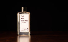 Transparent bottle standing upright on a wooden surface in a dark room